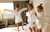 three girls are jumping on the bed wearing white bathrobes